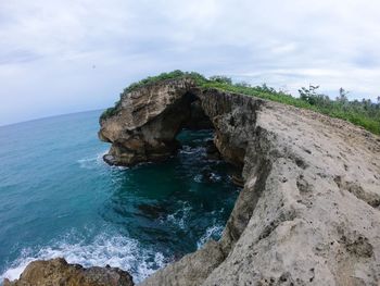 Rock formation in sea against sky