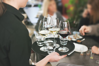 Midsection of woman holding beer glass on table at restaurant