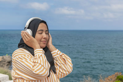 Smiling maghrebi woman with hijab listening to music