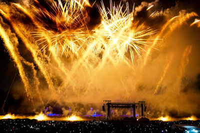 Crowd during concert against firework display at night