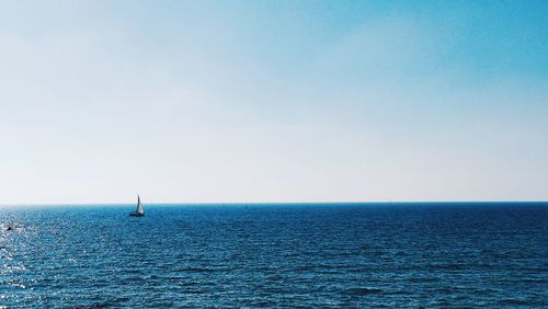 Sailboat sailing in sea against clear sky