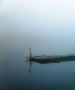 Pier over calm lake during foggy weather