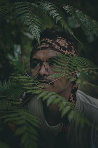 Close-up of young man standing amidst plants outdoors