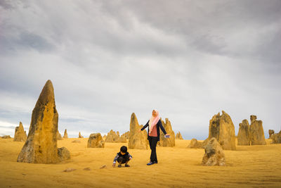 Panoramic view of man standing on rock against sky