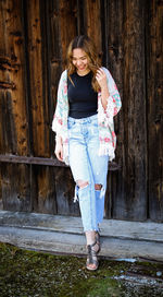 Portrait of a smiling young woman standing against wall