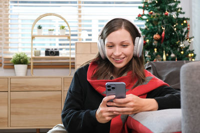 Young woman using mobile phone while sitting on sofa at home