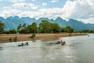 People rafting in river against sky