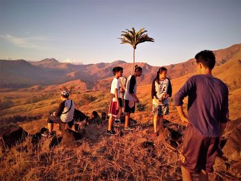 Friends standing on mountain against sky