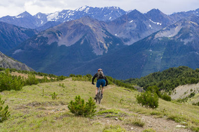 Rear view of man riding a bicycle on mountain