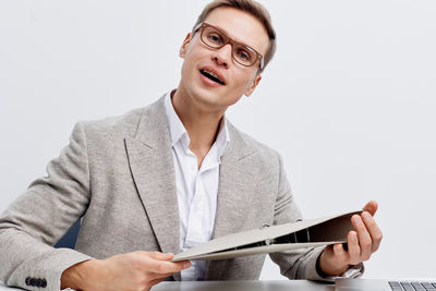 Portrait of businessman holding book against white background