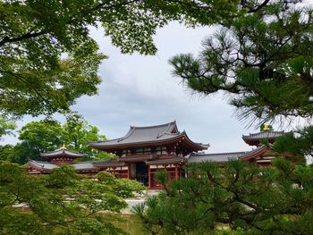 Building by trees against sky