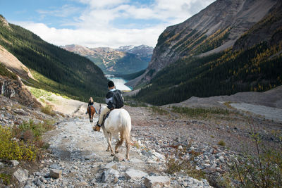 Rear view of horse riding horses on mountain