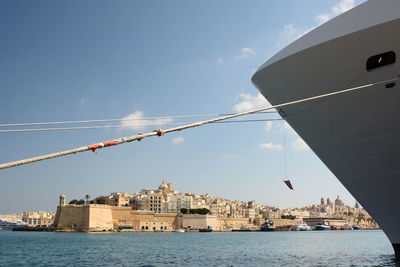 Sailboats in sea by buildings against sky