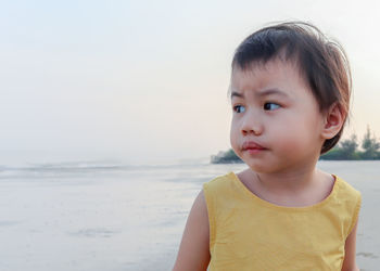 3 years asian girl, little toddler child standing with worried expression on the beach.