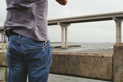 Rear view mid section of a man overlooking calm sea