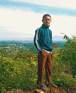 Portrait of smiling man standing on field against sky