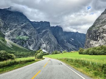 Road by mountains against sky