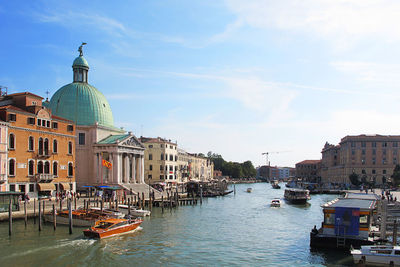 Boats in canal amidst buildings in city against sky