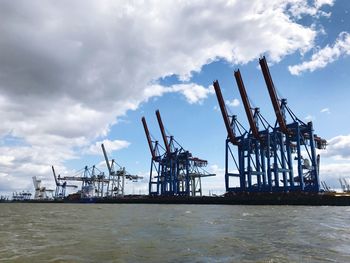 Cranes at commercial dock against sky