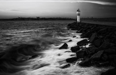 Lighthouse by sea against sky