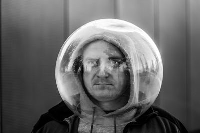 Man wearing spherical shape glass against wall