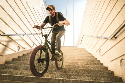 Low angle view of young man riding bicycle on steps