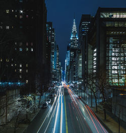 Light trails on road against buildings at night