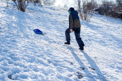 Rear view boy walking on snow covered land