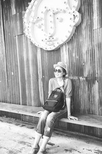 Full length of young woman sitting on wall