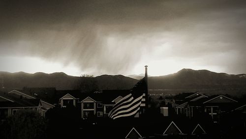 Houses on mountain against cloudy sky