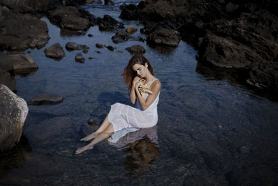 Portrait of a woman in a white dress sitting in the sea