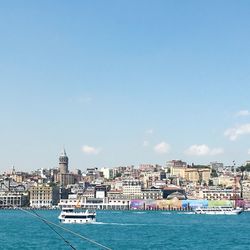 Boats in sea by cityscape against sky