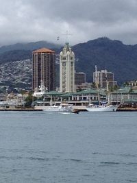 View of river and buildings against cloudy sky