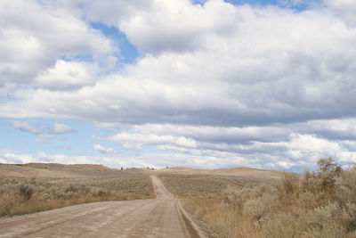 Road amidst field against sky