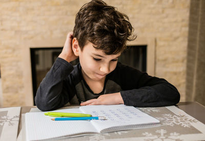 Cheerful and funny schoolboy solves  homework emotionally. thinks about how to solve math examples 