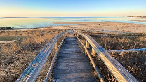 Boardwalk leading towards sea against sky