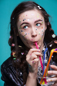 Young woman with various stickers on face and hands having drink