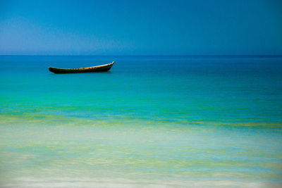 Boat in sea against clear blue sky