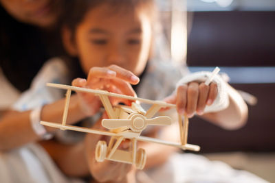 Midsection of mother and daughter holding model airplane in hospital