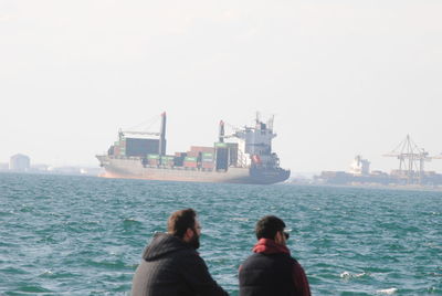 Rear view of men on boat against sky