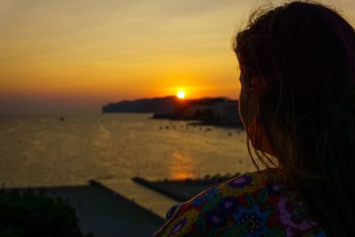 Silhouette of woman looking at sea during sunset