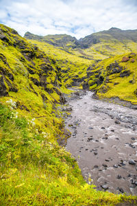 Scenic view of stream flowing amidst landscape against sky