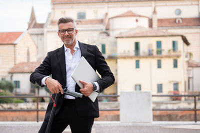 Businessman standing with electric scooter