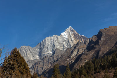 Low angle view of snowcapped mountains against blue sky