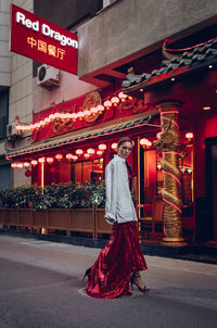 Woman standing by illuminated red light in city