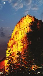 Low angle view of illuminated building against sky during sunset