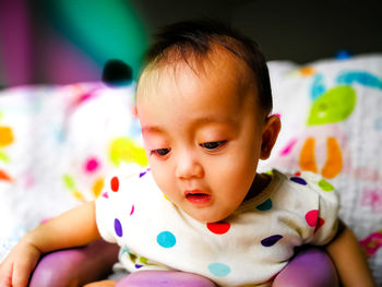 Close-up of cute baby girl drooling while sitting on chair at home