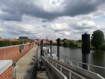 Bridge over river by buildings in city against sky