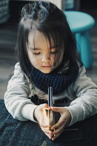 High angle view of cute girl holding smart phone on bed