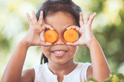 Girl covering eyes with carrot slices